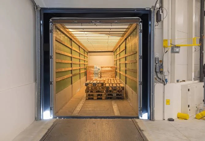 Open loading bay with pallets of goods stacked inside a trailer at a loading dock, ready for transport.